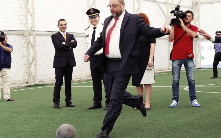 Martin Schulz tritt, umringt von Journalisten, einen Fußball.