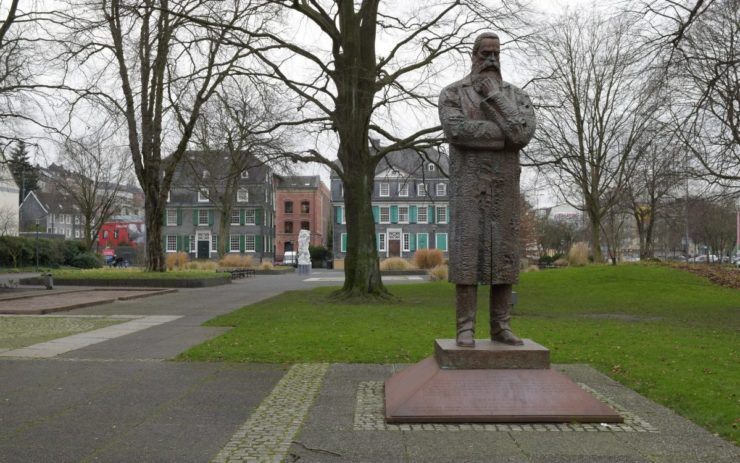 Die Statue von Friedrich Engels in Wuppertal. Stehend mit Hand am Bart. Anderer Arm ist verschränkt.