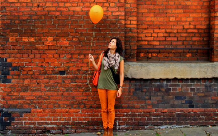 Frau mit Luftballon vor Mauer,