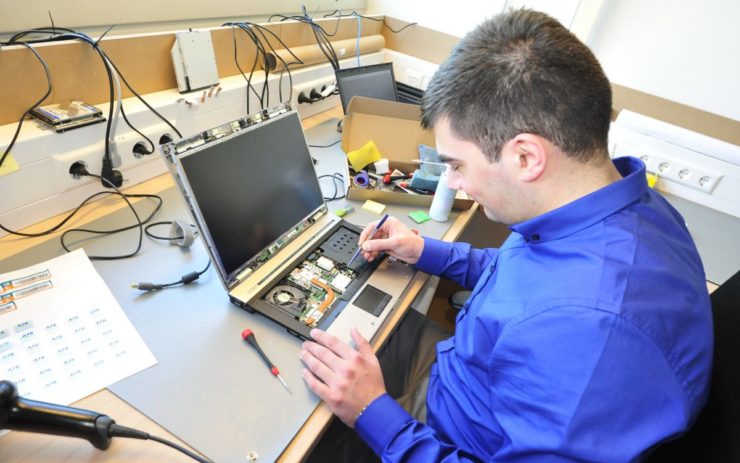 Mann mit Handicap am Arbeitsplatz, repariert Laptop