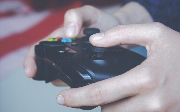 Spiele gibt es bei Gamestop: Eine Hand spielt mit einem Controller ein Videospiel