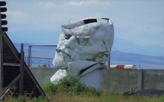 In einer heruntergekommen Landschaft steht eine kaputte Lenin Statur. Wiederaufbau als Lösung der Klimakrise?