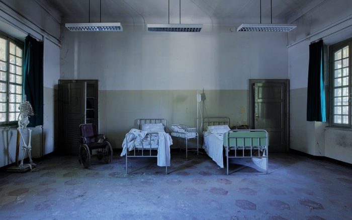 Eine triste Pflege-Einrichtung mit zwei Betten und kaputten Wänden