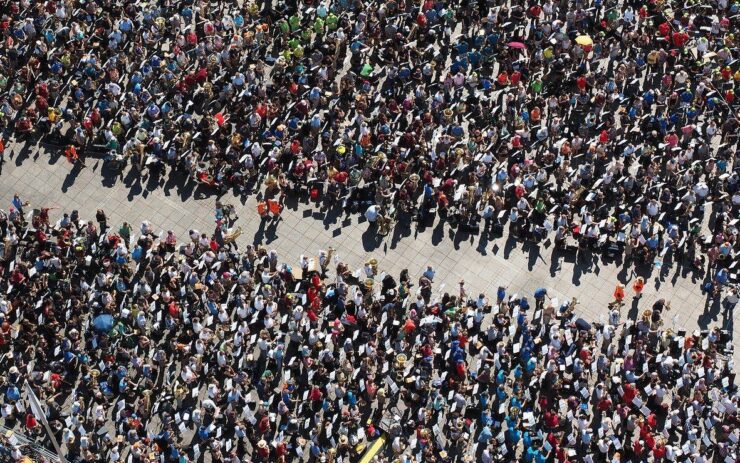 Eine Menschenmenge steht auf einem Platz. In ihrer Mitte bildet sie eine Gasse.