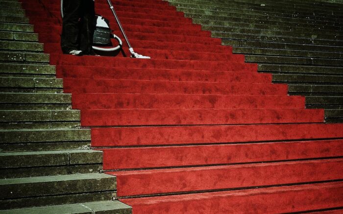 Eine Person saugt einen roten Teppich auf einer Treppe