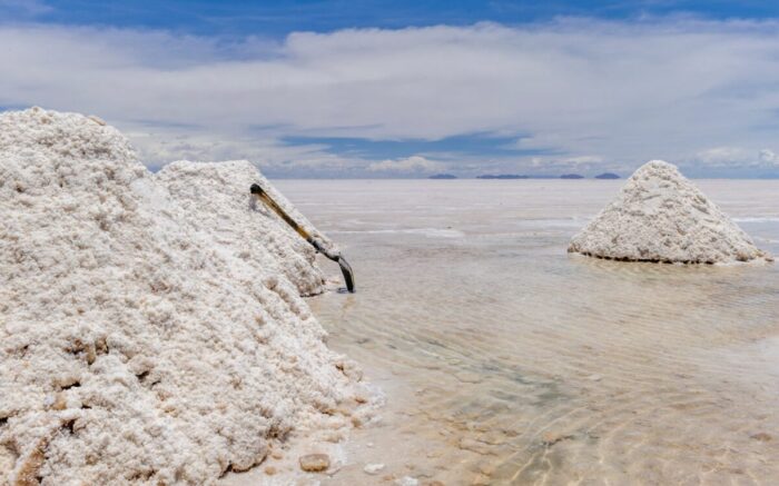 Weiße Salzhaufen in einem See. An einem lehnt eine Harke