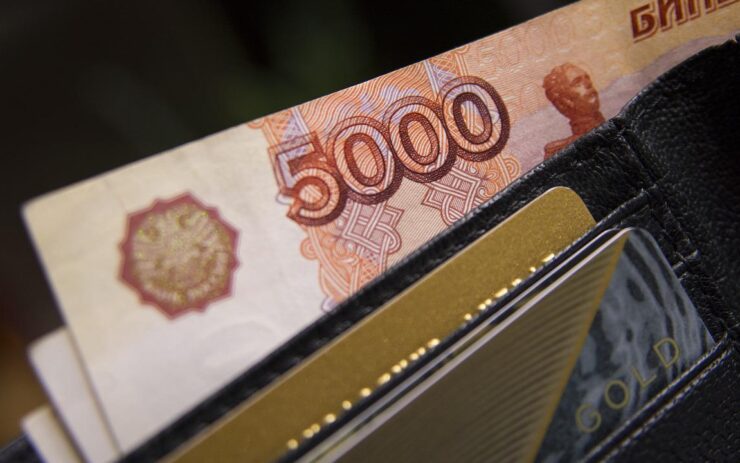 Aus einem Portemonnaie ragt eine Rubelnote (die Währung von Russland) heraus.