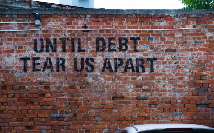 Graffiti auf einer Wand: "Until Debt Team Us Apart"