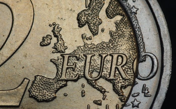 Eine Euro-Münze in Nahaufnahme. Man sieht den Euro-Schriftzug vor einer Karte von Europa.