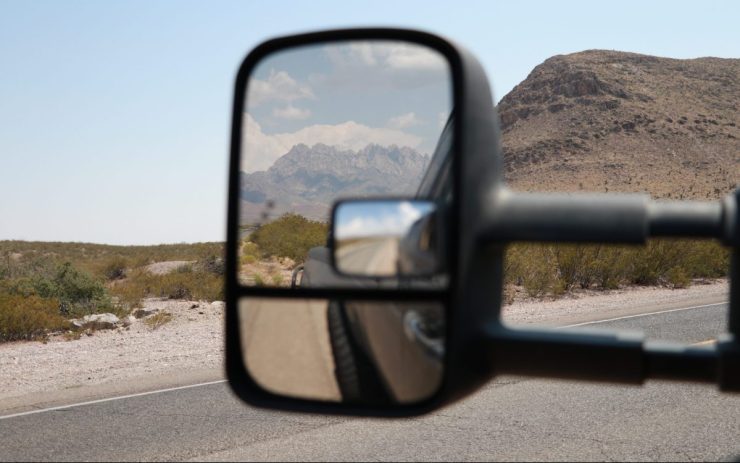 In einem Auto-Rückspiegel sieht man einen Berg