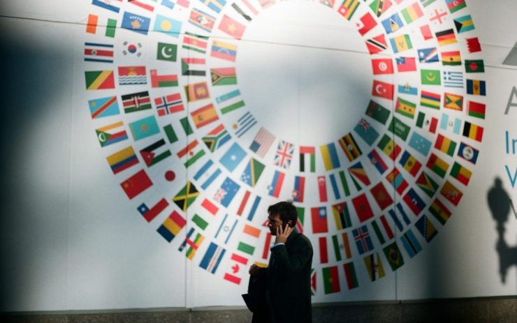 Ein Mann im Anzug telefoniert im Foyer der Weltbank vor einem Wandbild mit den Fahnen der Mitgliedsstaaten der Organisation.