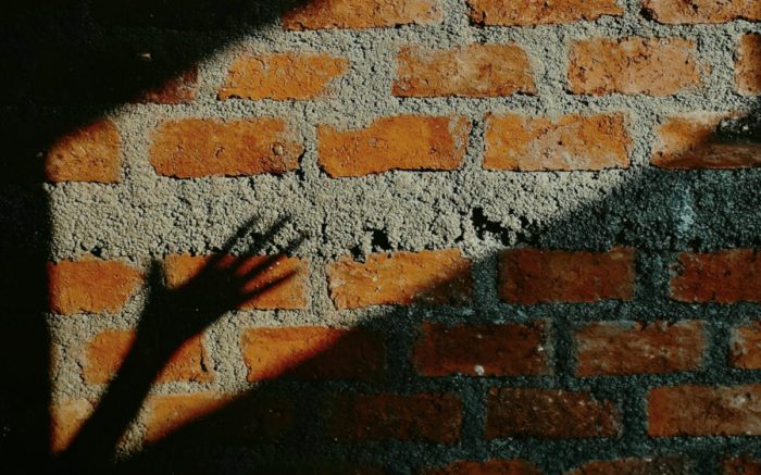 Der Schatten einer Hand auf einer Mauer